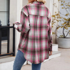A person wearing an oversized fit, long-sleeved plaid button-down shirt in shades of pink, grey, and white with blue jeans is standing outdoors with their back to the camera.