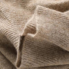 A close-up of a soft, beige cashmere blend knitted fabric with a fuzzy texture, perfect for autumn winter layering, showing overlapping folds and ribbed edges.