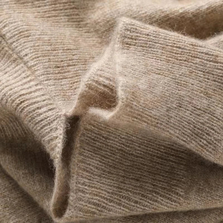 A close-up of a soft, beige cashmere blend knitted fabric with a fuzzy texture, perfect for autumn winter layering, showing overlapping folds and ribbed edges.