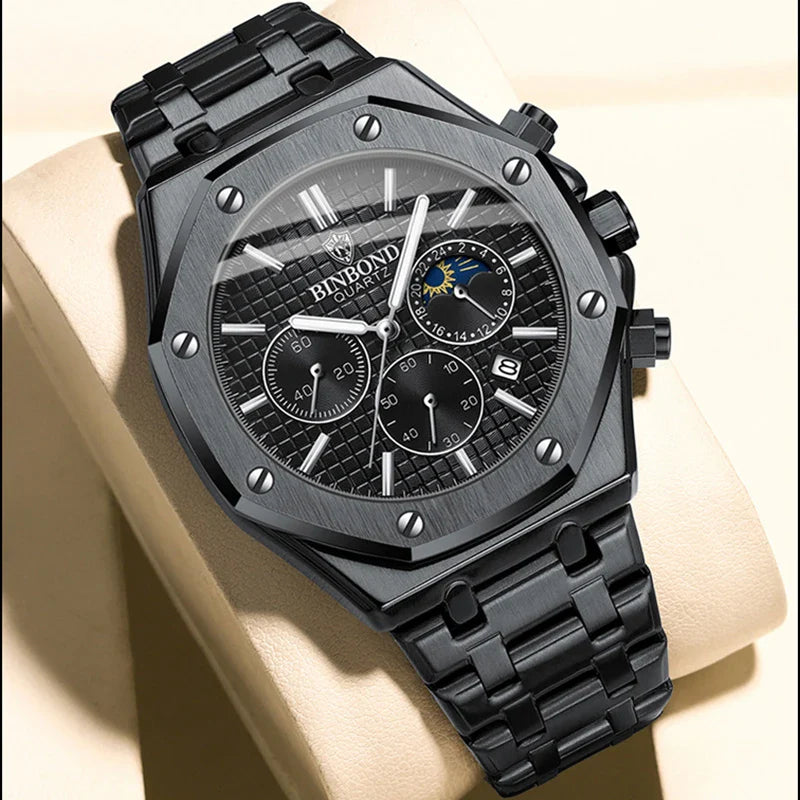 A black stainless steel watch with a geometric bezel features chronograph dials, a date window, and moon phase indicator. Displayed on a beige cushion, its face reads BINFOND QUARTZ and showcases precision quartz movement.