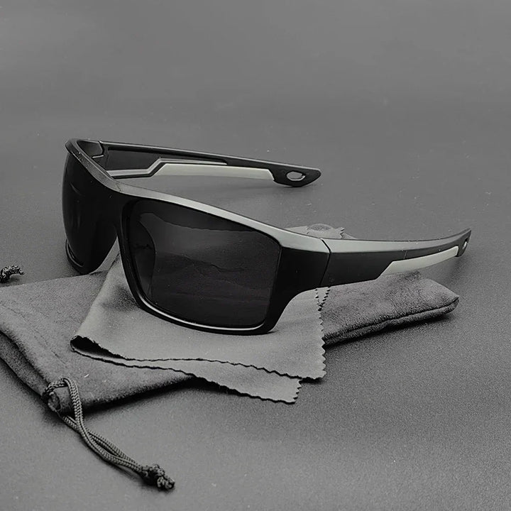 A pair of black rectangular Everest Sunglasses with thick frames and polarized lenses rests on a gray drawstring pouch and cleaning cloth, all placed on a plain gray surface.