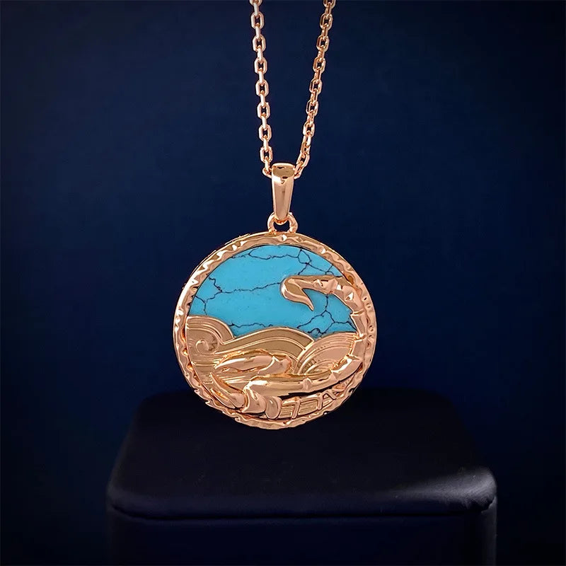 A round gold pendant with a chain, featuring a turquoise stone inlaid with gold waves and a whale tail design, this zodiac necklace is beautifully displayed against a dark background.