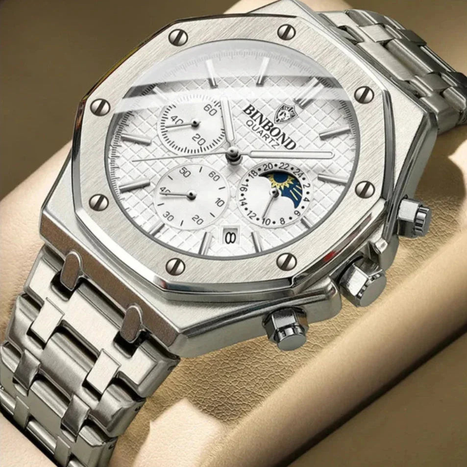 A silver Bimbond luxury stainless steel watch with chronograph dials, white textured dial, date display, moonphase indicator, hexagonal bezel, and precision quartz movement, displayed on a beige watch cushion.