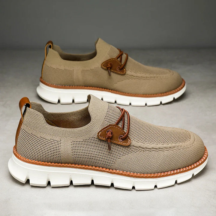 A pair of light brown breathable loafers with white chunky soles, mesh fabric uppers, brown leather details, and decorative laces, displayed on a neutral background.
