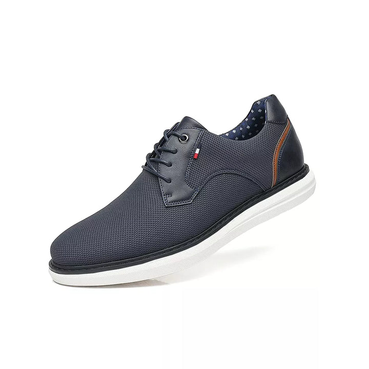 A navy blue lace-up casual shoe with a textured upper, white sole, and subtle brown and red accent details, featuring traditional detailing inspired by luxury mens shoes, displayed against a white background.