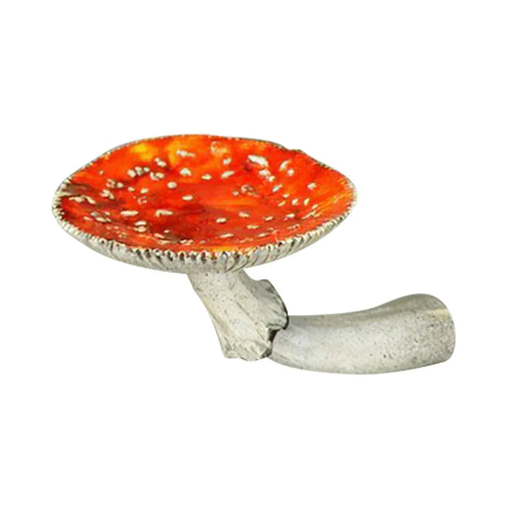 A ceramic object shaped like a red and white spotted mushroom cap with a short, curved, gray stem resembling a whimsical pipe—perfect as unique home decor. The background is plain white.