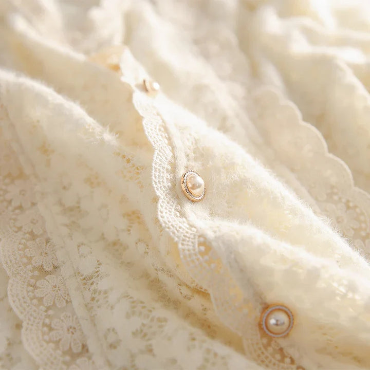 Close-up of an ivory lace blouse with vintage pearl buttons, featuring a soft, intricate floral lace pattern and scalloped edges.
