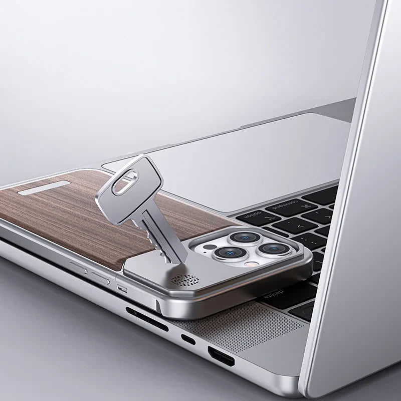 A key is inserted into a smartphone with a stylish phone case, partly tucked under a laptop, creating an illusion that the phone works like a USB drive. The devices are placed on a light gray surface.