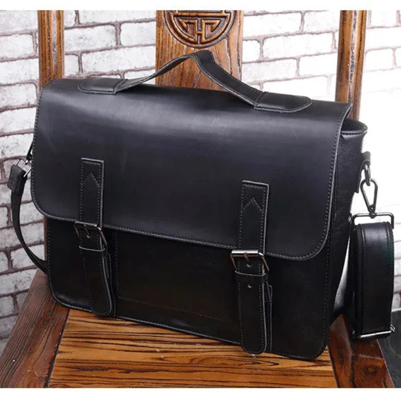 A black premium leather satchel with buckle straps and an adjustable shoulder strap rests on a wooden chair with ornate carvings, set against a white brick wall background.