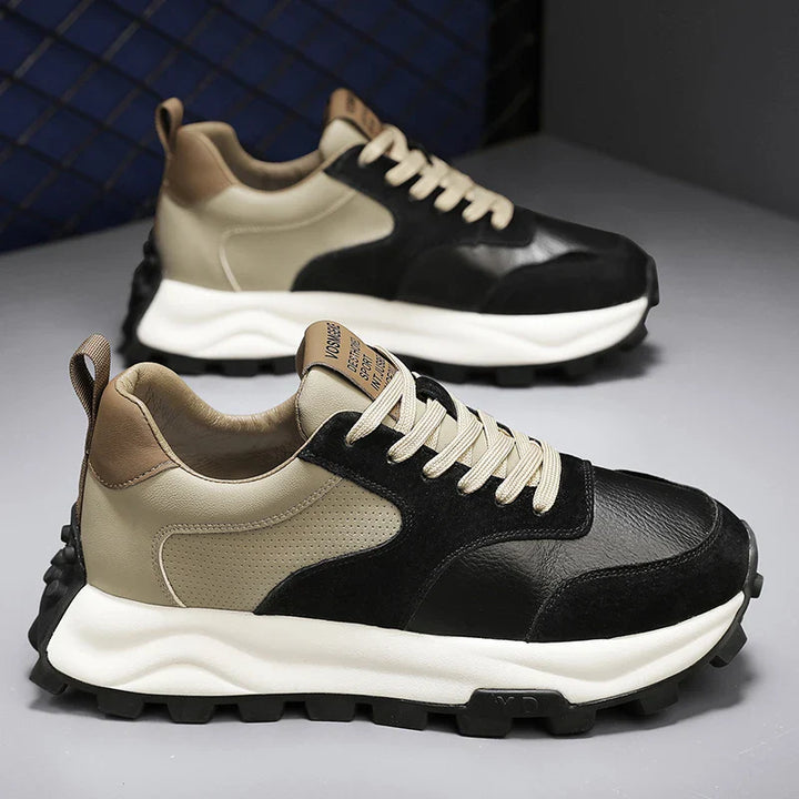A pair of modern Onex Street Sneakers with beige and black panels, chunky white soles, beige laces, brown heel tabs, and cloud-like cushioning. Textured outsoles add grip, all displayed against a gray background with a blue mesh accent.