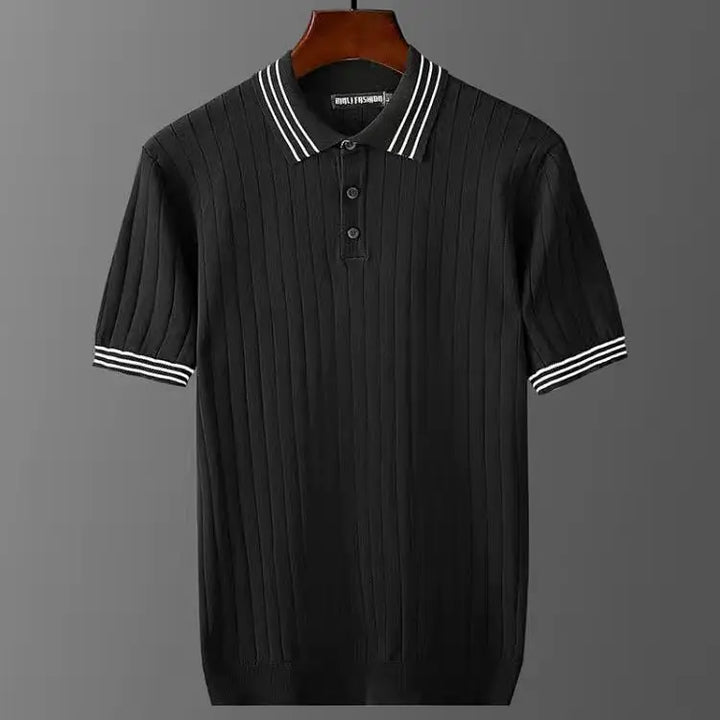 A premium polo shirt in black with vertical ribbed texture, button-up collar, and white stripes on the collar and sleeve cuffs, displayed on a hanger against a gray background.