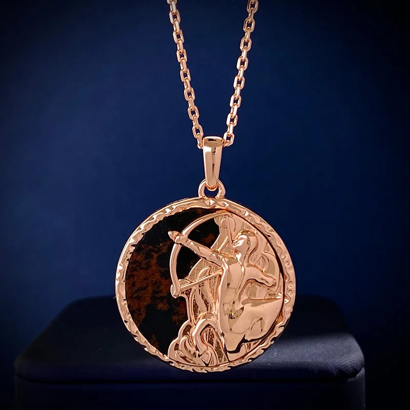 A gold zodiac necklace featuring a raised archer drawing a bow, set against a dark, round background and displayed on a chain with a deep blue backdrop.