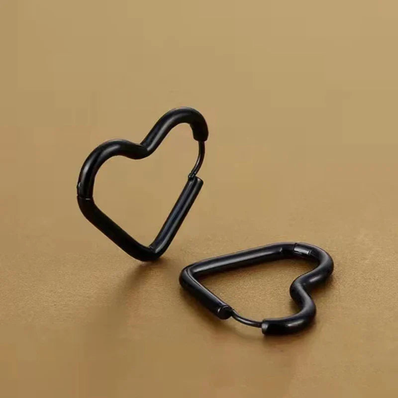 Two black heart-shaped carabiner clips, featuring minimalist design, are displayed on a plain brown surface—one standing upright and the other lying flat.