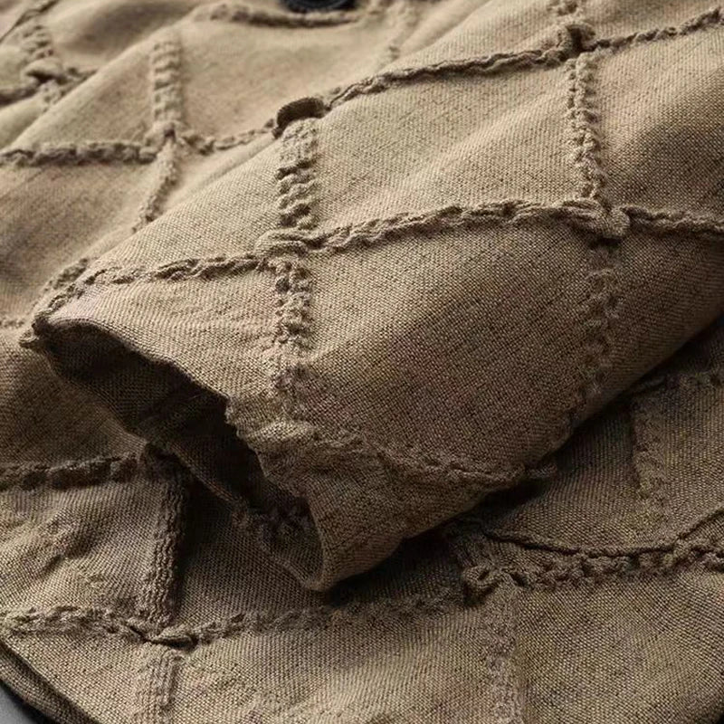 A close-up of brown fabric with a quilted diamond pattern. The stitching creates raised, grid-like diamonds across the material, and a folded section is visible in the foreground—perfect for luxury two-piece sets or relaxed fit trousers.