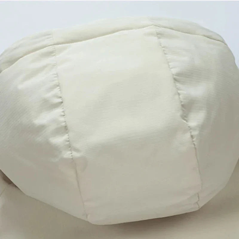 A close-up view of an off-white, padded, and quilted fabric object, possibly an insulated cushion or section of soft furniture, with visible stitching and seams.