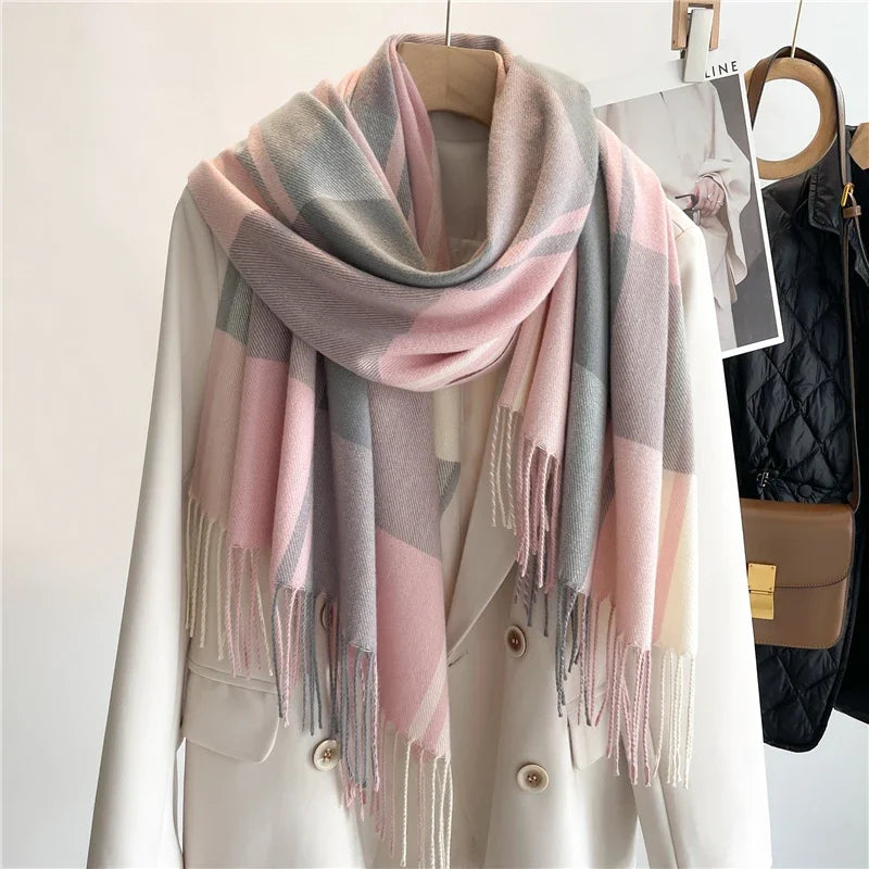 A cream-colored coat on a hanger with a soft, lightweight plaid scarf in pastel pink, gray, and beige tones draped around the collar; a brown bag and black jacket hang in the background.