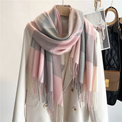 A cream-colored coat on a hanger with a soft, lightweight plaid scarf in pastel pink, gray, and beige tones draped around the collar; a brown bag and black jacket hang in the background.