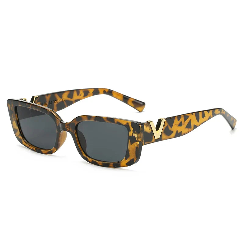 Tortoiseshell designer sunglasses with square dark lenses, thick geometric frames, UV400 protection, and gold V detailing on the temple arms, displayed against a white background.