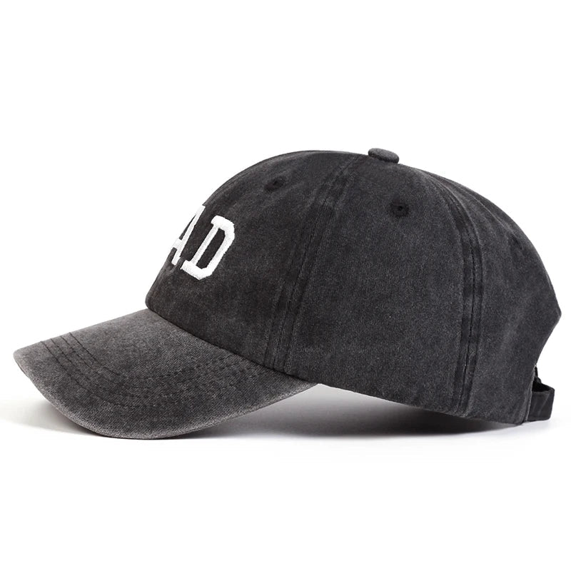 A black embroidered cap with white text on the front, styled in classic vintage streetwear fashion and shown from the side against a white background.