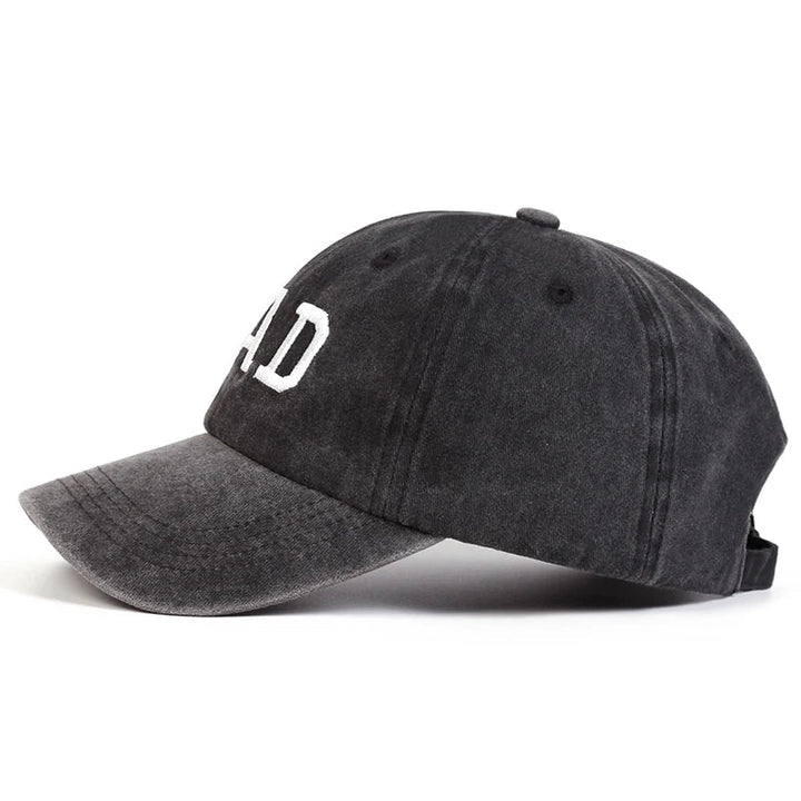 A black embroidered cap with white text on the front, styled in classic vintage streetwear fashion and shown from the side against a white background.