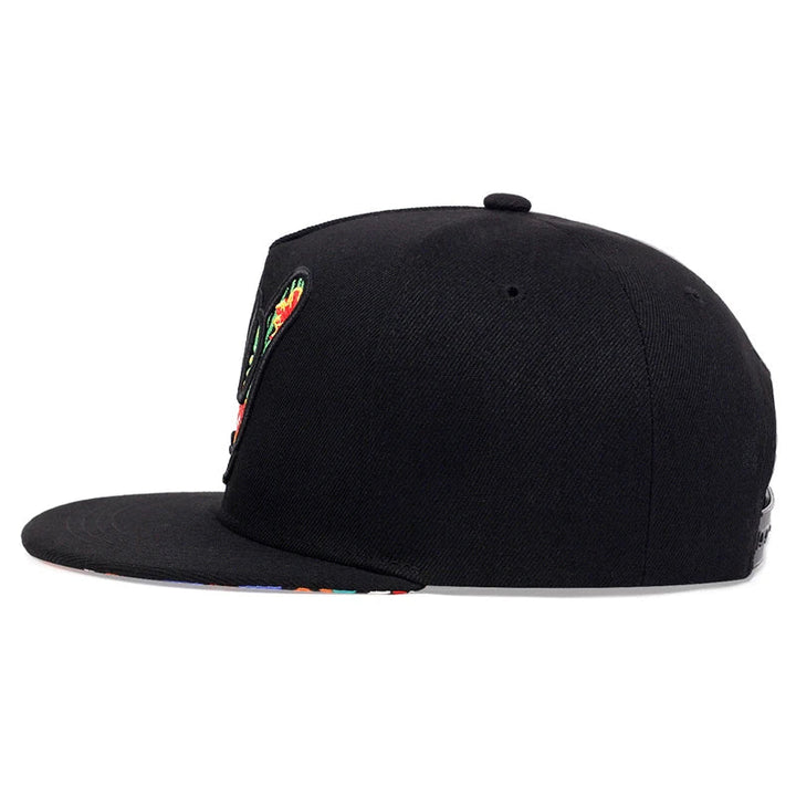 A black flat-brim tropical snapback hat shown from the side, featuring a colorful design on the brim and the front left panel.