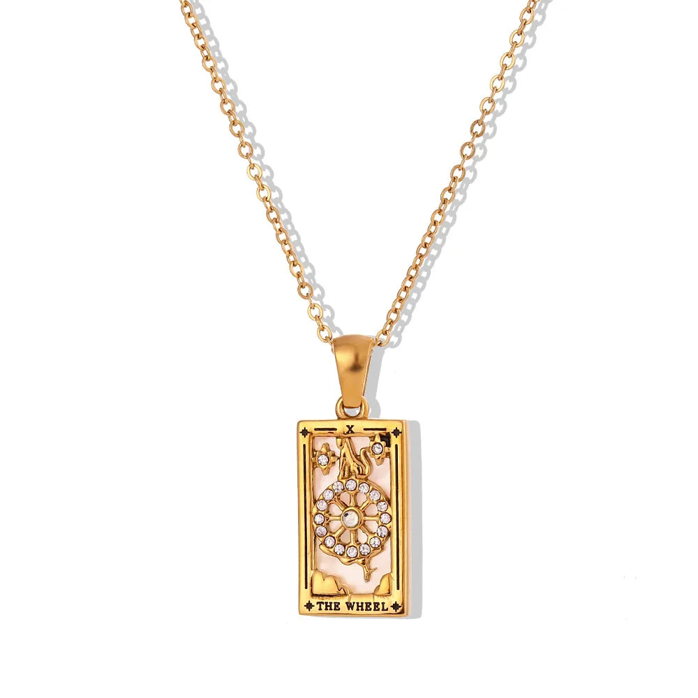 The Solaris Pendant Necklace features a rectangular tarot card pendant labeled The Wheel, crafted in 18K gold-plated metal with a central wheel accented by small clear gemstones. The pendant hangs elegantly from a matching gold chain.