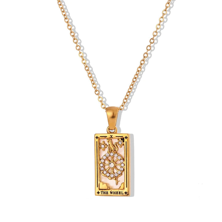 The Solaris Pendant Necklace features a rectangular tarot card pendant labeled The Wheel, crafted in 18K gold-plated metal with a central wheel accented by small clear gemstones. The pendant hangs elegantly from a matching gold chain.