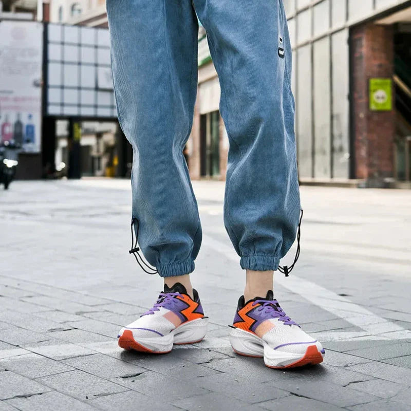 Person standing on a city street wearing light blue jogger pants and colorful sneakers with a shock-absorbing sole. The shot is focused on their legs and shoes with buildings in the background.