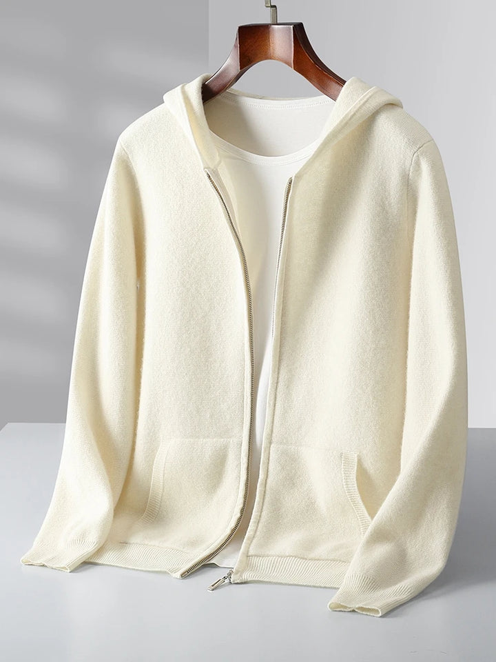 A cream-colored zip-up hoodie with pockets, displayed on a hanger over a white T-shirt, perfect as an autumn winter cardigan, set against a light background.