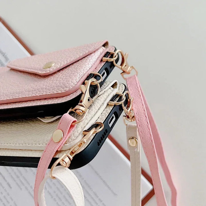 Close-up of two smartphones in pebble-texture material leather wallet cases with gold hardware, cardholder pocket, and matching straps—one light pink and one cream—stacked together against a neutral background.