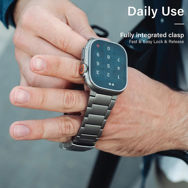 A person wearing a smartwatch with a Grade 2 Titanium metal band on their wrist, displaying a numeric keypad. Text on the image reads Daily Use and Fully integrated clasp Fast & Easy Lock & Release, highlighting adjustable lightweight durability.