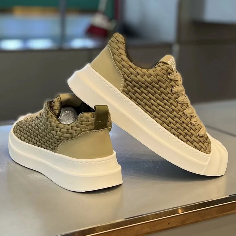 A pair of beige woven upper sneakers with thick white cushioned soles displayed on a reflective surface; one shoe stands upright while the other lies on its side, showing both the side and back views of these lightweight shoes.