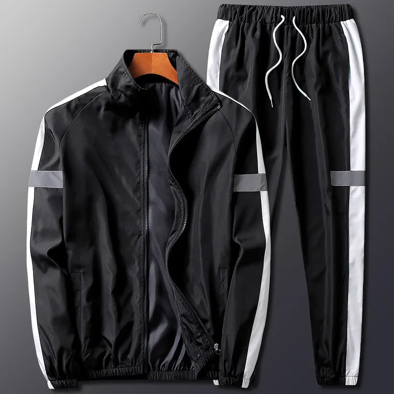 A black two-piece activewear set with white side stripes, featuring a zip-up jacket with a stand collar and matching pants with an elastic waistband and white drawstrings. Ideal for moisture wicking comfort during workouts.