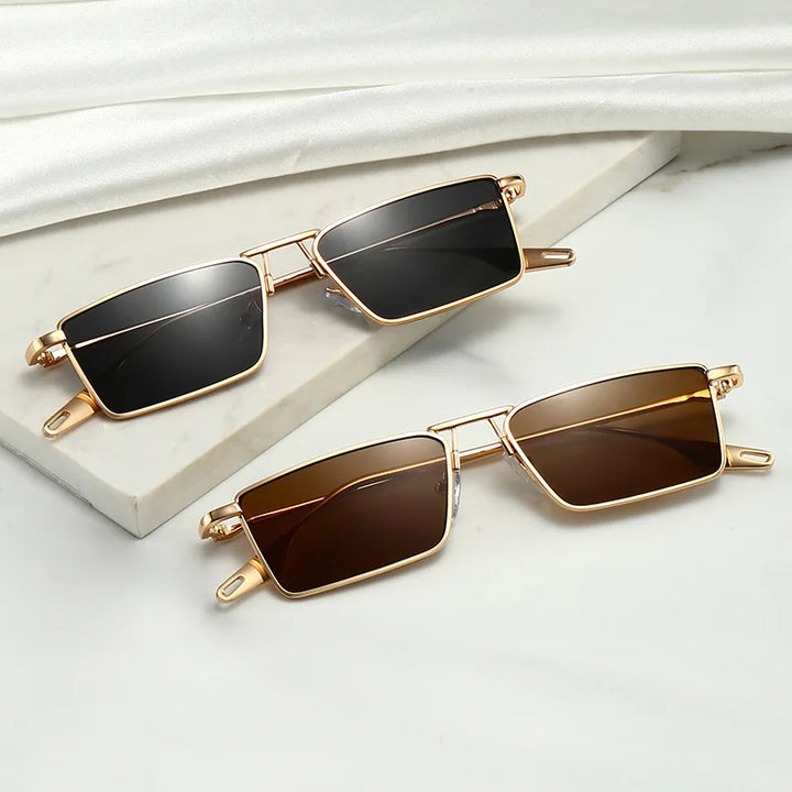 Two pairs of Avalon Sunglasses with gold frames and rectangular lenses—one with black and one with brown tints—are displayed on a marble surface, complemented by a white cloth in the background.