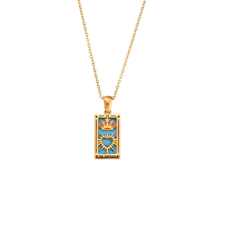 The Solaris Pendant Necklace is an 18K gold-plated chain with a rectangular blue enamel pendant, featuring a sunburst design, crown, and the words The Empress at the bottom, evoking the beauty of a tarot card.