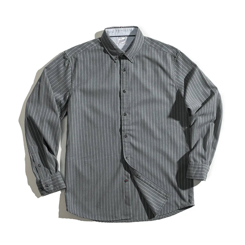 A gray, long-sleeve pinstripe shirt with white vertical stripes, made from fine weave cotton and laid flat on a white surface. The collar and cuffs have buttons, and the wrinkle-resistant fabric appears neatly arranged.