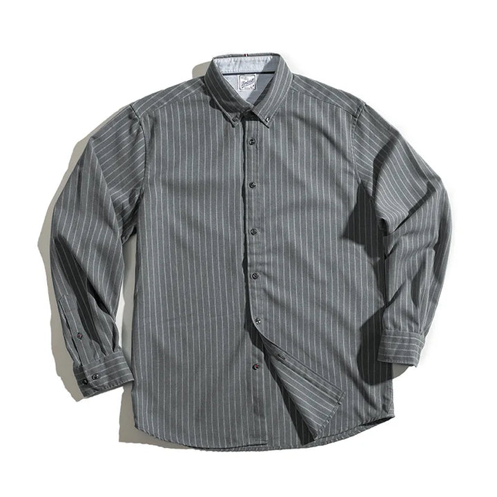 A gray, long-sleeve pinstripe shirt with white vertical stripes, made from fine weave cotton and laid flat on a white surface. The collar and cuffs have buttons, and the wrinkle-resistant fabric appears neatly arranged.