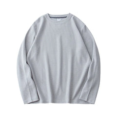 Light gray, heavyweight long-sleeve shirt laid flat on a white background. The premium cotton fabric has a subtle ribbed texture and appears soft and comfortable. The shirt features a relaxed, casual fit.