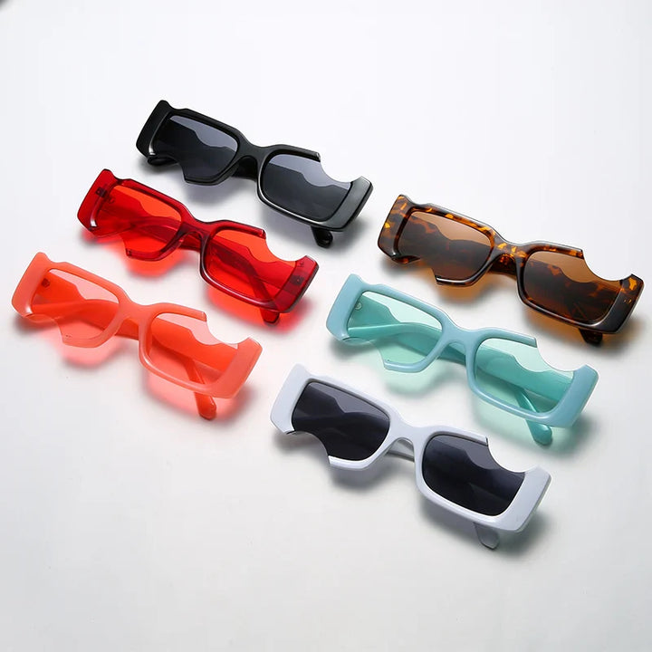 Six pairs of geometric frame rectangular sunglasses in black, red, tortoiseshell, coral, mint green, and light blue are arranged neatly on a white surface for the perfect street style look.