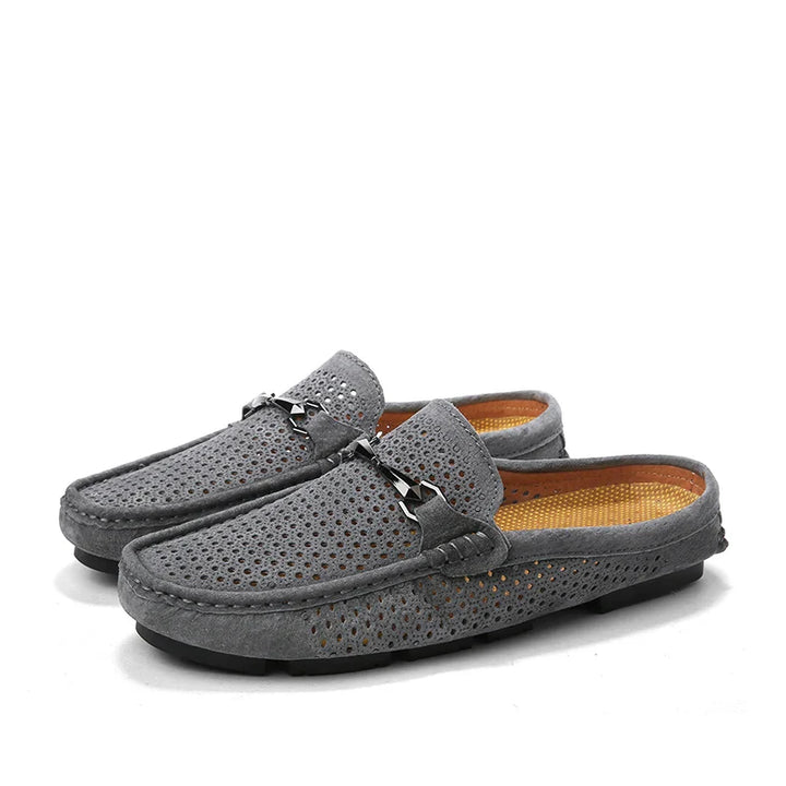 A pair of gray, perforated breathable loafers with textured soles and a decorative metal bit across the top, featuring a light brown insole—perfect summer shoes for casual comfort.