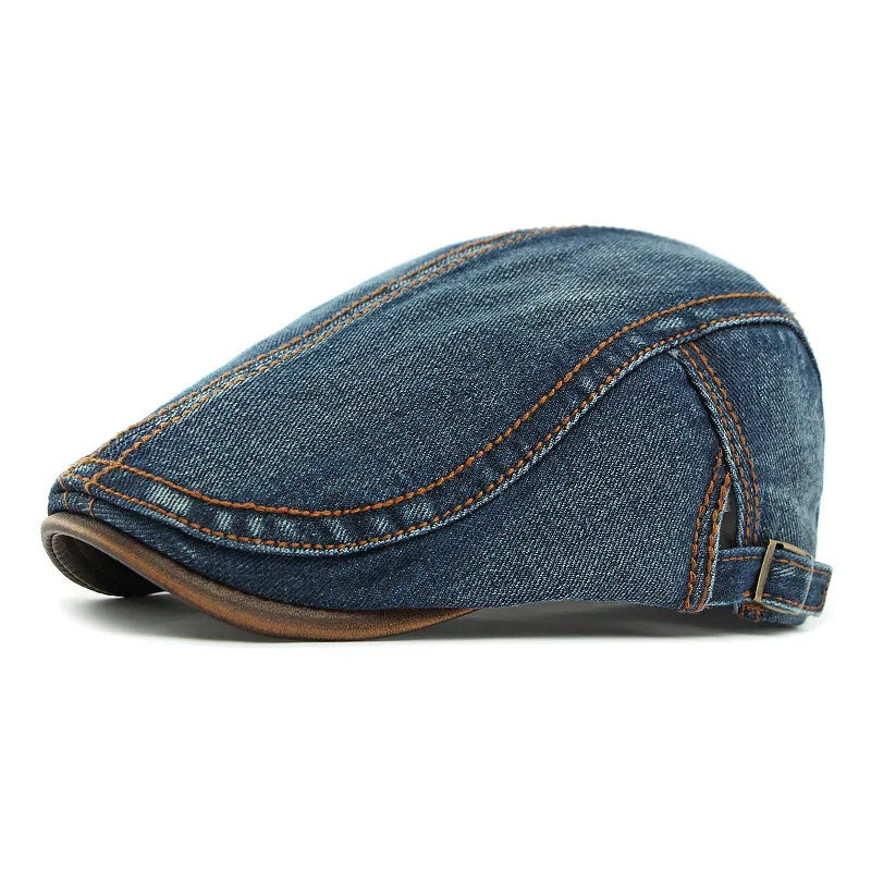 A unisex blue denim flat cap with orange stitching, brown trim along the edge, and an adjustable strap at the back offers both style and sun protection.
