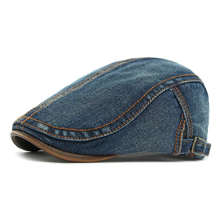 A unisex blue denim flat cap with orange stitching, brown trim along the edge, and an adjustable strap at the back offers both style and sun protection.