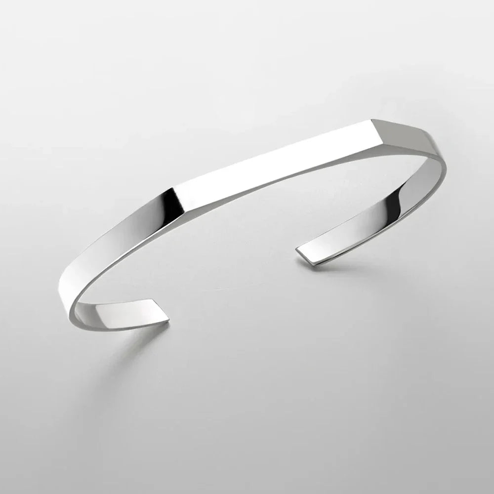 A minimalist cuff bracelet with a sleek, polished surface and open-ended design, crafted in stainless steel with 18K gold plating, displayed on a plain light gray background.