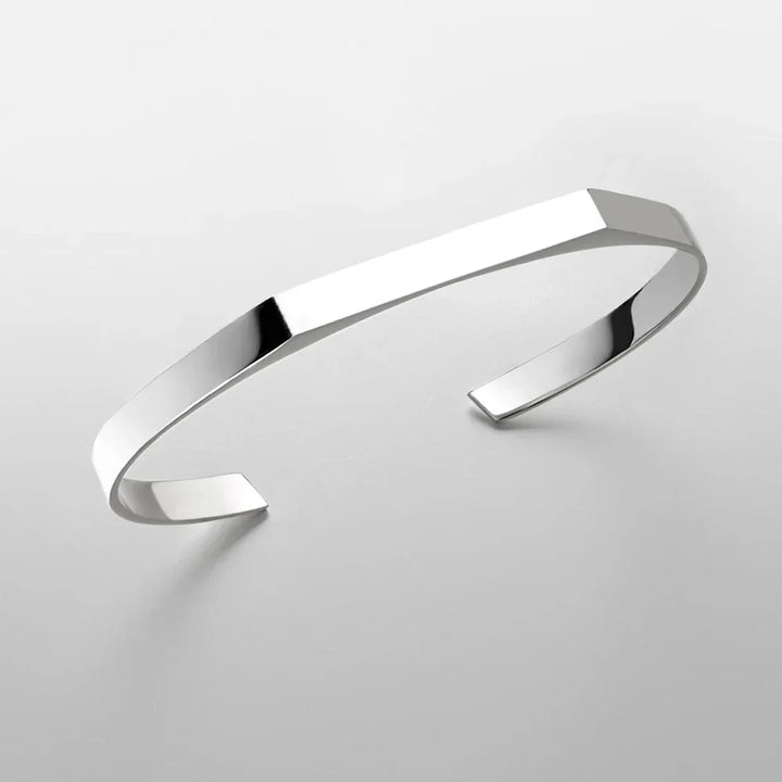 A minimalist cuff bracelet with a sleek, polished surface and open-ended design, crafted in stainless steel with 18K gold plating, displayed on a plain light gray background.