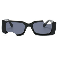 A pair of rectangular black sunglasses with dark lenses, featuring a distinctive cut-out notch on the lower left side of the frame—perfect for elevating your street style with bold geometric frames.