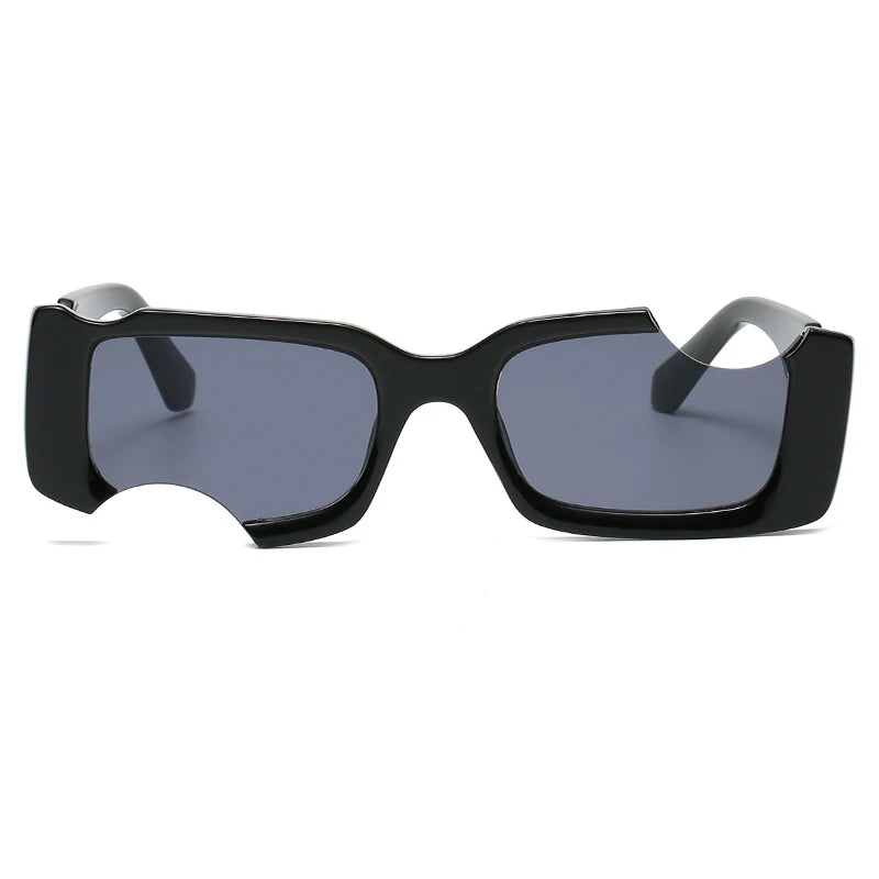 Black rectangular avant-garde sunglasses with thick frames and dark lenses, featuring an unusual cut-out section on one side of the bottom frame. These irregular sunglasses offer UV400 protection against harmful rays. The background is plain white.