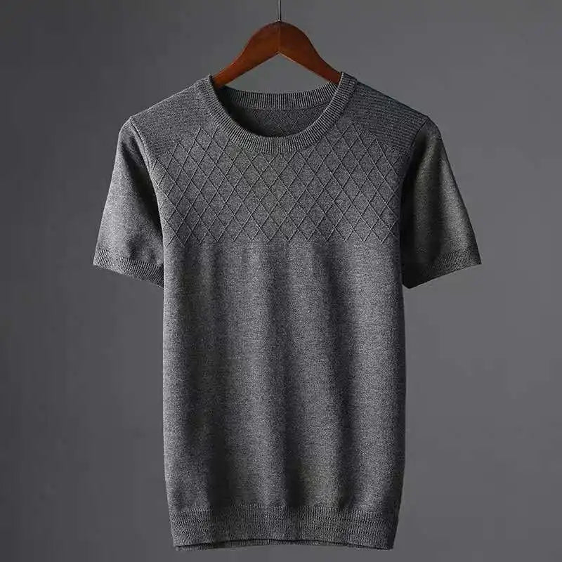 A short-sleeved, gray knit sweater with a diamond-pattern across the chest, hanging on a wooden hanger against a plain gray background.