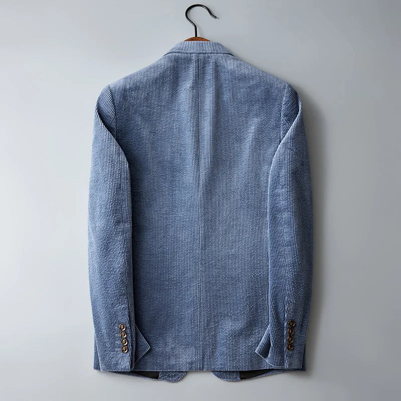 A light blue slim-fit corduroy blazer hangs on a black hanger against a plain light gray background, shown from the back with visible sleeve buttons and subtle texture.