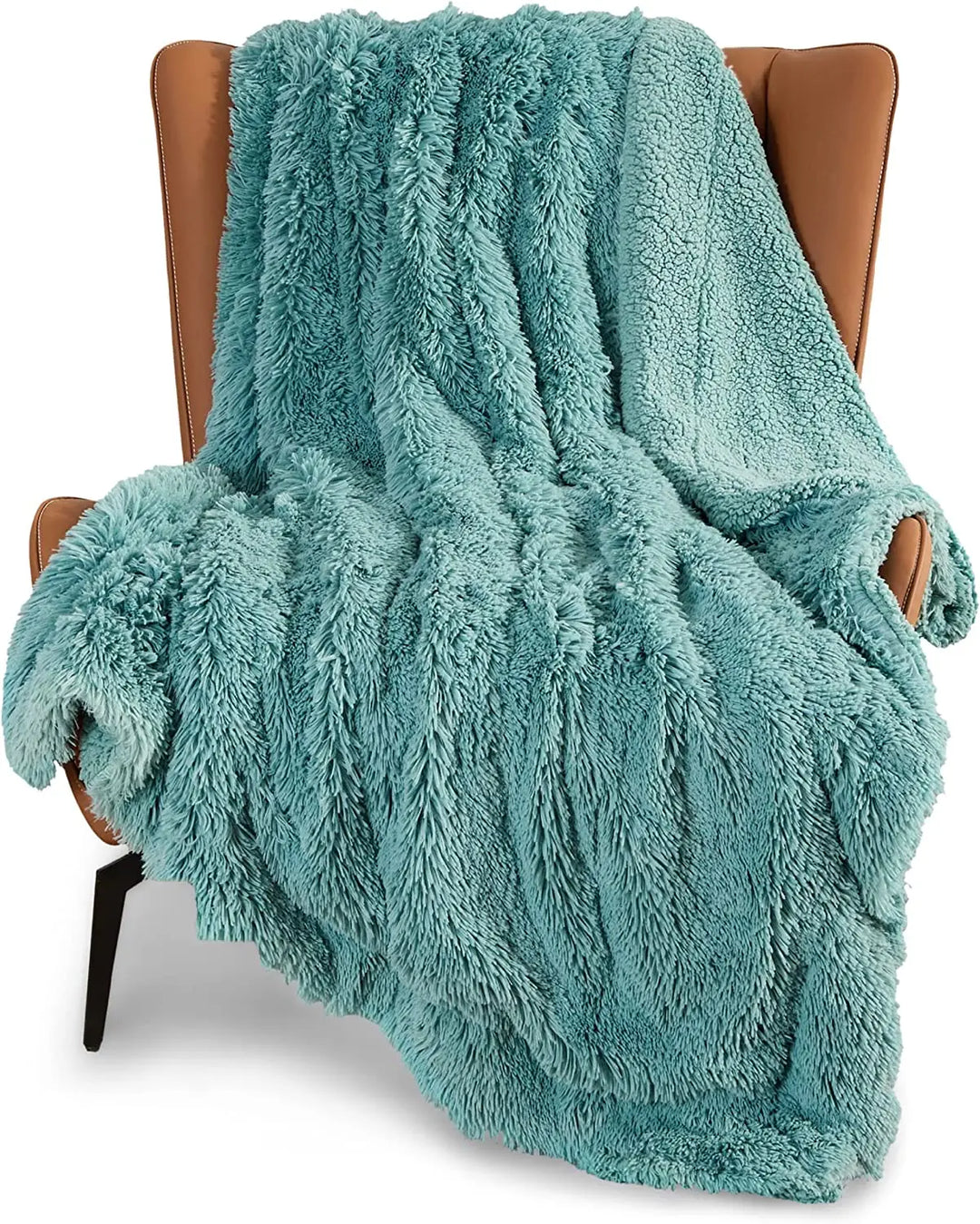 A soft, sage green faux fur throw blanket draped over a brown leather armchair with angled arms and black legs.