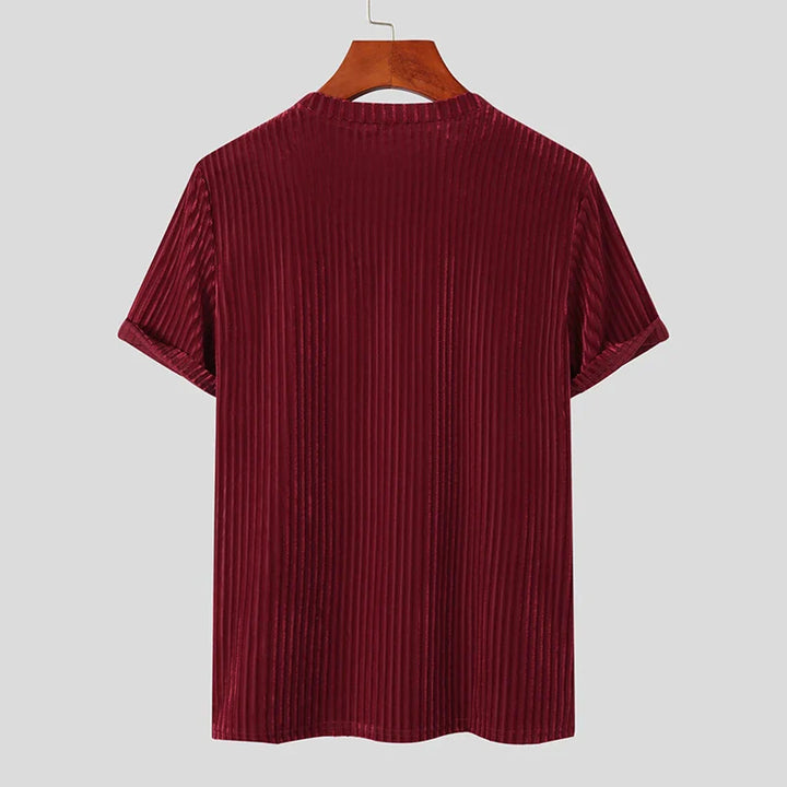 A short-sleeved, stripe corduroy tee in deep burgundy with a classic fit, displayed on a wooden hanger against a plain light gray background, shown from the back.